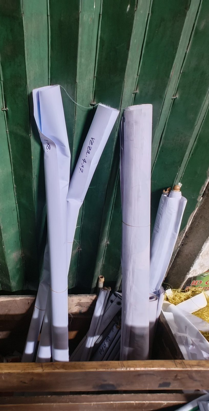 Rolled discarded banners stacked against a green shop door