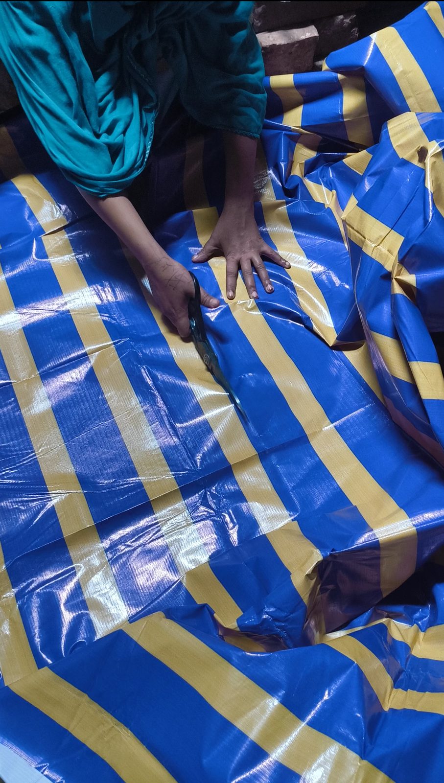 An artisan cutting a blue and yellow banner with scissors