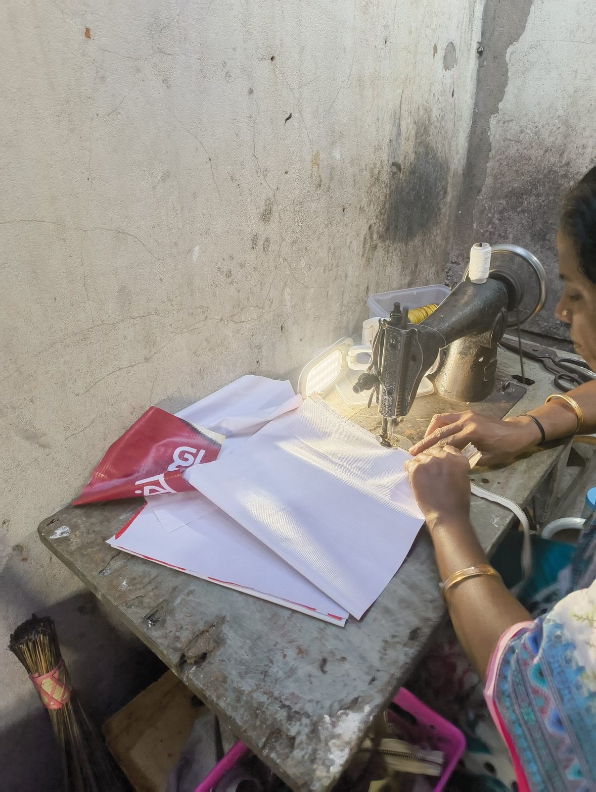 An artisan guiding white banner pieces through a sewing machine